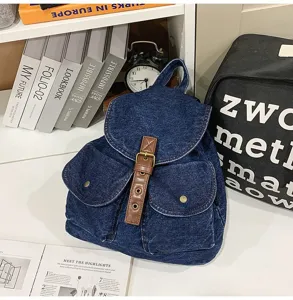 Detailed view of a blue denim backpack with classic leather buckle and flap cover.