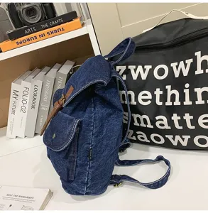 Detailed side view of a stylish blue denim backpack placed in a modern study setting