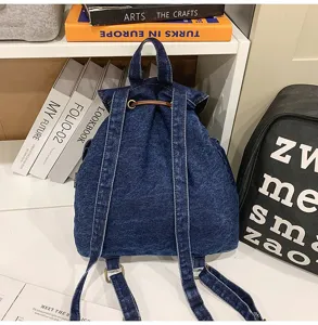 Back view of a casual blue denim backpack with adjustable straps and drawstring top.