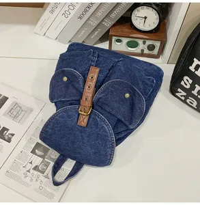 Detailed top view of a stylish blue denim backpack on a desk with books and clock