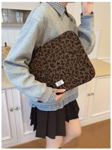 Person holding a stylish leopard print laptop sleeve in a cozy indoor setting.