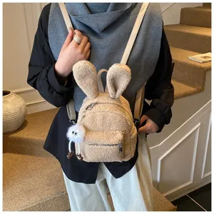 Detalle de mochila de felpa beige con orejas de conejo y colgante de pompón suave