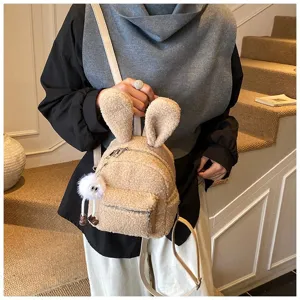 Vista detallada de la linda mochila de felpa beige con orejas de conejo usada por una modelo