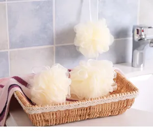 Vista macro detallada de esponjas de baño grandes de color crema en una cesta tejida.