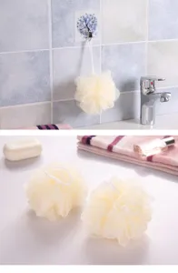 Primer plano de esponjas de baño de malla color crema en un baño limpio y moderno.