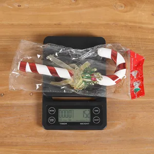 Détail d'un ornement de canne de Noël en plastique sur une balance pesant 15,2g.