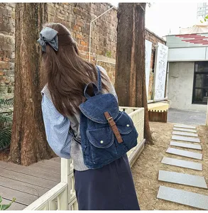 Detailed view of a navy blue denim backpack worn outdoors in a natural park setting