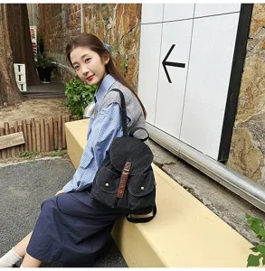 Stylish large capacity black denim backpack for school and travel shown on model outdoors