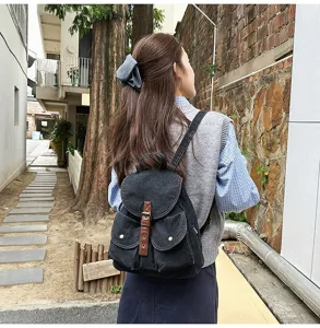 Back view of a casual black denim backpack worn by a woman outdoors