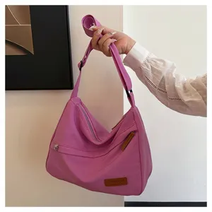 Grand sac à bandoulière en toile violette avec sangle réglable et fermetures éclair tenu à la main