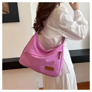 Modèle à la mode portant un grand sac à bandoulière en toile rose dans une pièce épurée