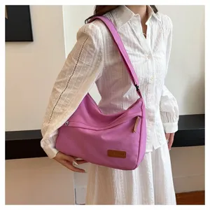 Détail d'un grand sac à bandoulière en toile violette porté par un mannequin.