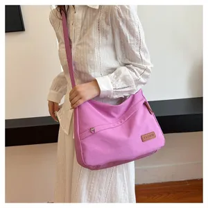 Détail d'un sac à bandoulière en toile violette porté par un mannequin au quotidien