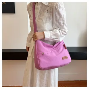Grand sac à bandoulière en toile rose porté par un mannequin de mode actuel