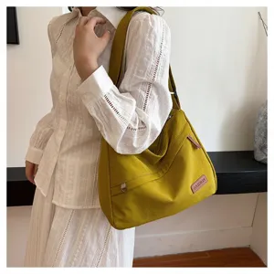 Grand sac à bandoulière en toile jaune moutarde porté par un mannequin, style décontracté.