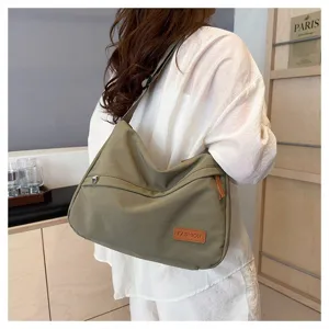 Gros plan d'un sac bandoulière en toile vert olive porté sur une tenue décontractée