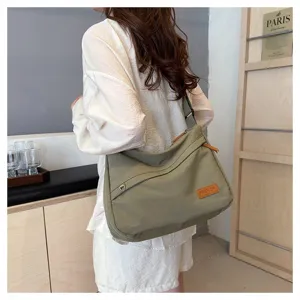 Vue détaillée du grand sac bandoulière en toile vert olive sur mannequin.