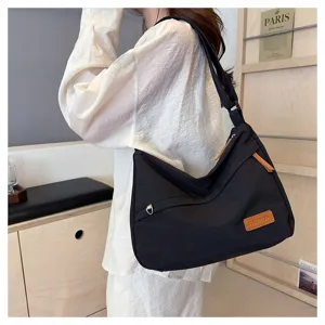 Sac bandoulière noir minimaliste de grande capacité présenté par un mannequin chic