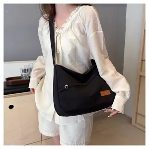 Gros plan d'un mannequin portant un grand sac à bandoulière en toile noire dans une chambre