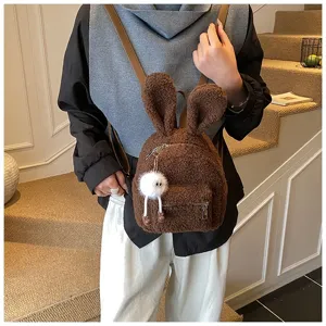Detalle de una mochila de felpa marrón con orejas de conejo y un amuleto blanco peludo
