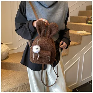 Primer plano de mochila de peluche marrón con orejas de conejo y colgante peludo