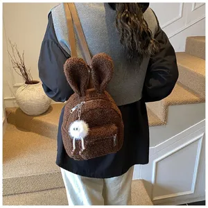 Mochila de peluche marrón con orejas de conejo y amuleto blanco, usada en interiores