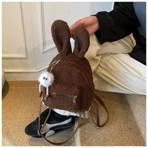 Primer plano de mochila de peluche marrón con orejas de conejo y colgante de peluche