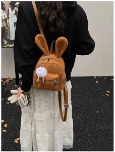 Vista trasera de una linda mochila de felpa marrón con orejas de conejo y falda blanca