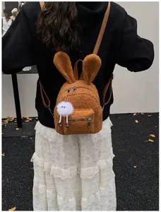 Vista trasera de una linda mochila de felpa marrón con orejas de conejo y dije