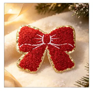 Close-up of a festive red chenille bow patch with gold glitter edge for Christmas DIY