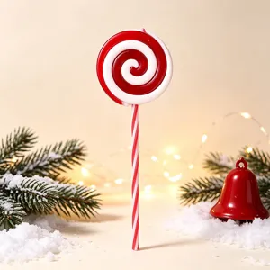 Festive red and white spiral Christmas lollipop ornament set in a snowy pine scene