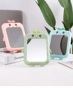 Close-up of three cute cartoon desk makeup mirrors in pastel pink, green, and blue.
