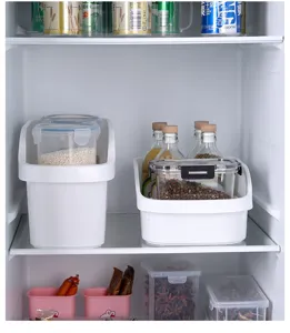 Detalle de cestas de plástico blanco para organizar alimentos y botellas dentro del frigorífico.