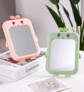 Detail view of cute pink and green grass sprout desktop mirrors on white tabletop.