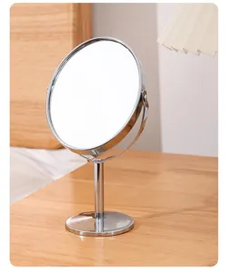 Elegant silver double-sided desktop makeup mirror on a warm wooden vanity table.