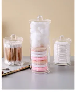Set of three transparent acrylic storage jars holding cotton swabs, pads and puffs.