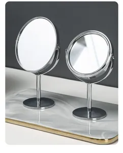 Detailed view of two chrome-plated desktop makeup mirrors on a marble tray