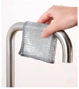 Detailed view of a silver wire cleaning cloth being used to scrub a stainless steel faucet.