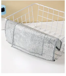 Detail shot of a silver wire cleaning cloth draped over a white metal wire basket.