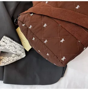 Detailed view of the brown quilted crossbody bag with cute white bow embroidery accents.