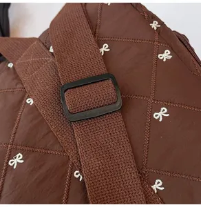 Close-up detail of brown quilted travel bag featuring adjustable strap and cute bow embro.