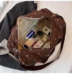 Quilted travel duffel bag with bow embroidery, spacious interior capacity, lightweight gym bag.
