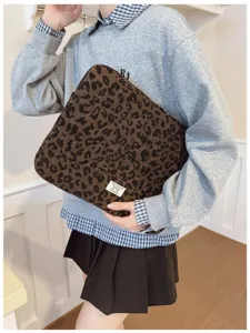 Lifestyle detail of a leopard print laptop sleeve held by a model.