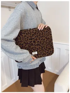 Close-up of leopard print laptop sleeve held by a person in a minimalist setting
