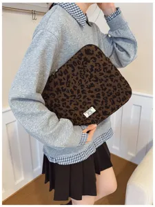 Close-up of leopard print laptop sleeve held by model showing fabric texture and scale