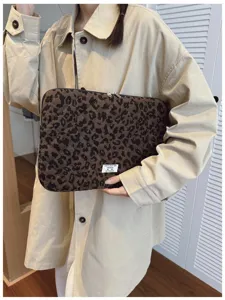 Stylish leopard print laptop sleeve bag being held by a model in a beige trench coat