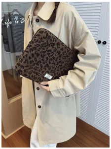 Close-up of a stylish leopard print laptop sleeve held by a model in a minimal setting.