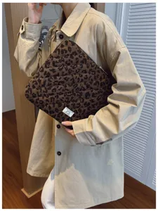 Leopard print laptop sleeve held by a person wearing a beige trench coat