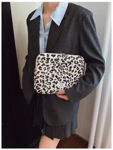 Model holding a chic leopard print laptop sleeve in a stylish charcoal grey blazer.