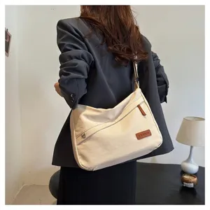 Vue arrière d'un sac bandoulière en toile crème porté avec un blazer gris décontracté